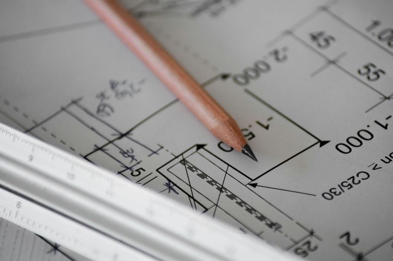 A close up of a blueprint with a pencil and ruler on top of it.