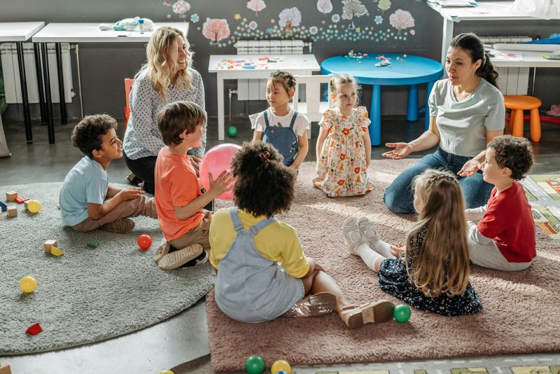 A colorful kindergarten classroom with engaged students interacting with each other and their teachers.