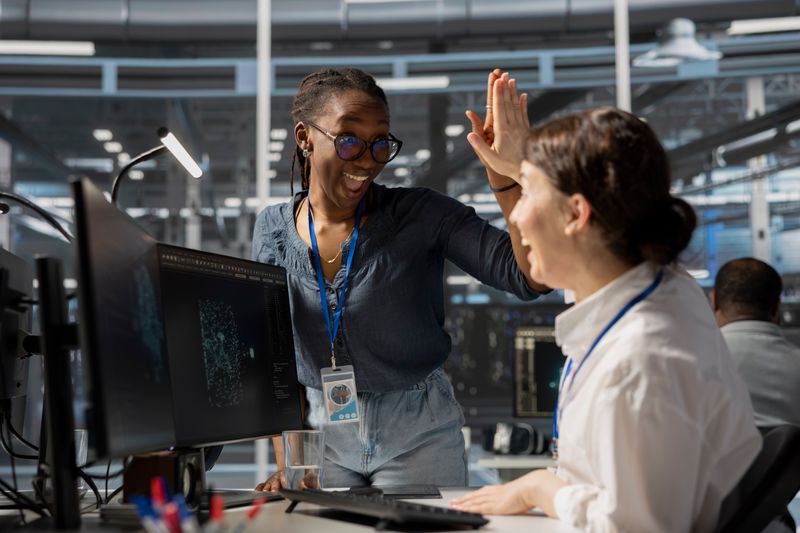 Two female colleagues high-fiving each other in an office.