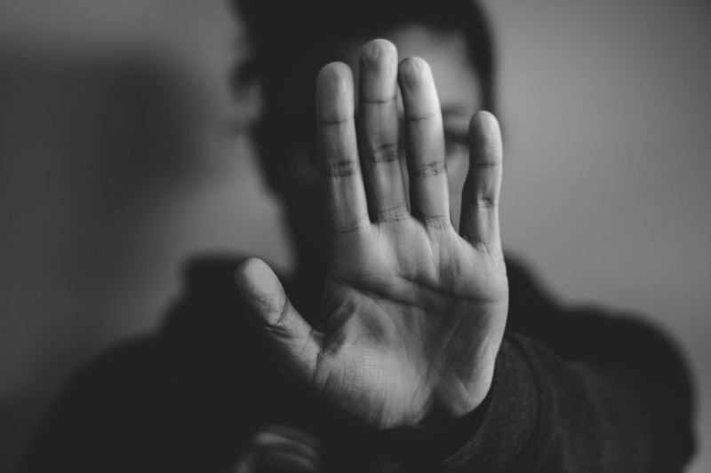 A black and white photo of a woman with her palm in front of her face. 