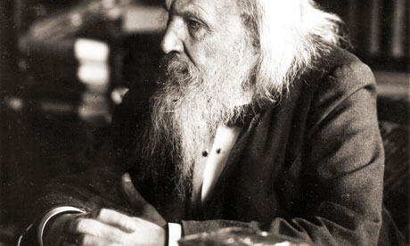 Alack and white photo of Mendeleev. He has long, white hair and a beard and is wearing a blazer, sitting, looking to the left