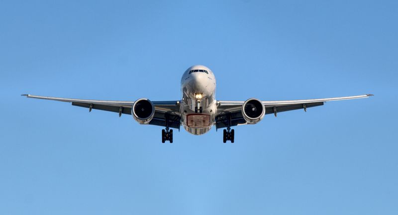 Airplane flying high in the air surrounded by pure blue sky.