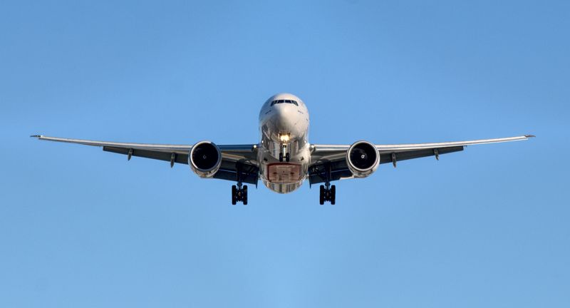 Airplane flying high in the air surrounded by pure blue sky. 