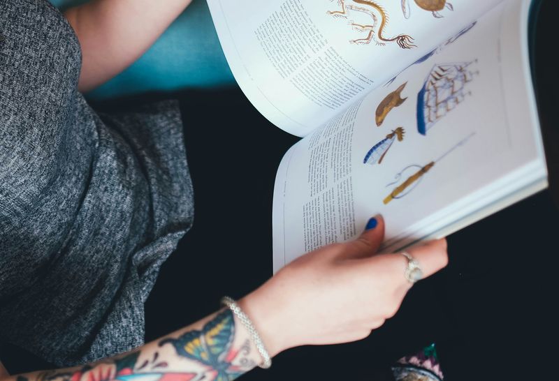 A person reading a book with text and images of blue and gold.