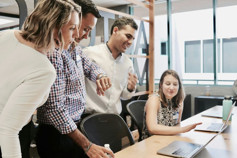 A group of coworkers discussing work while looking at a laptop.