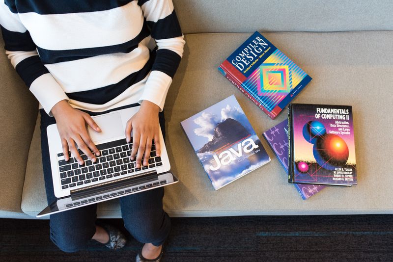 Books related to technology with a lady working on her laptop