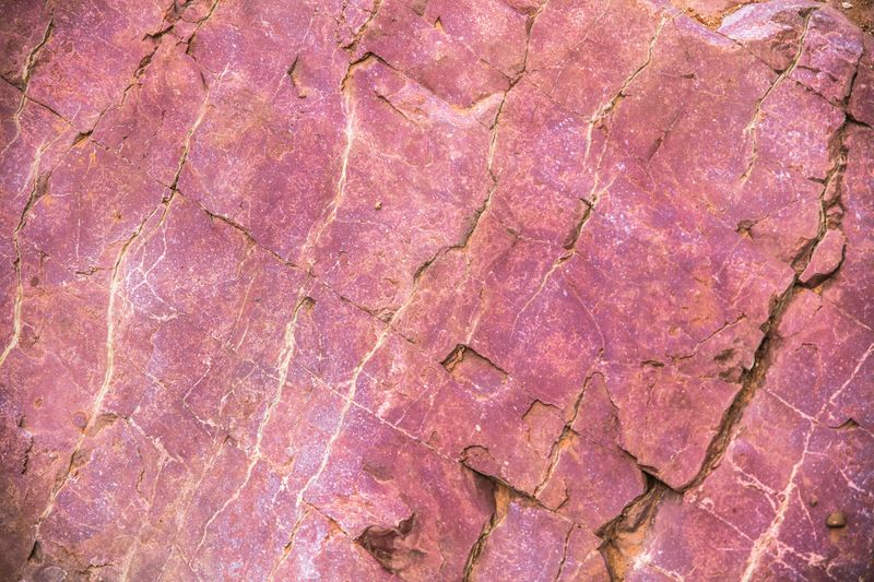 Red rock with white veins and cracks.