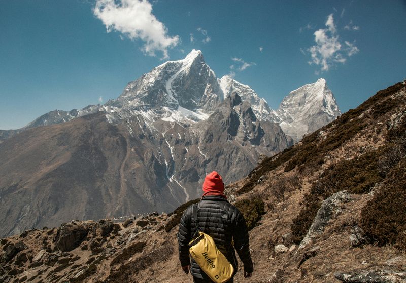 A person on a mountain hike looking towards the highest point of a peak.