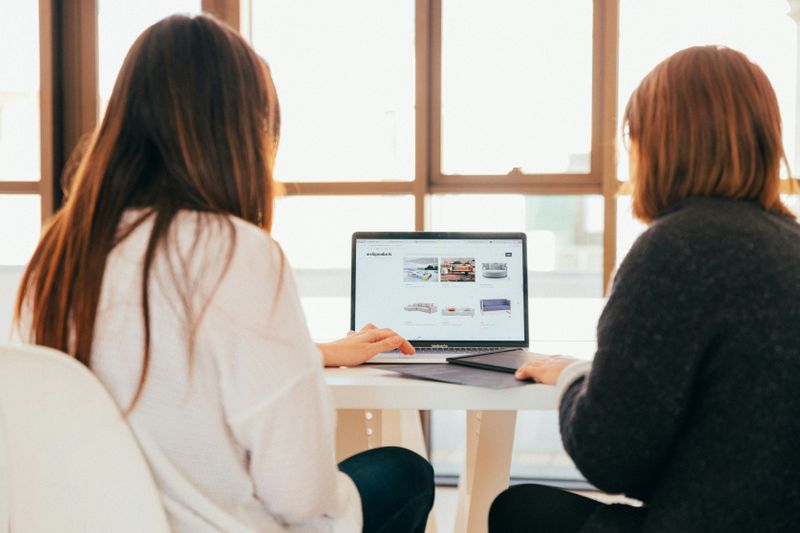 Two students looking at a laptop on a table.