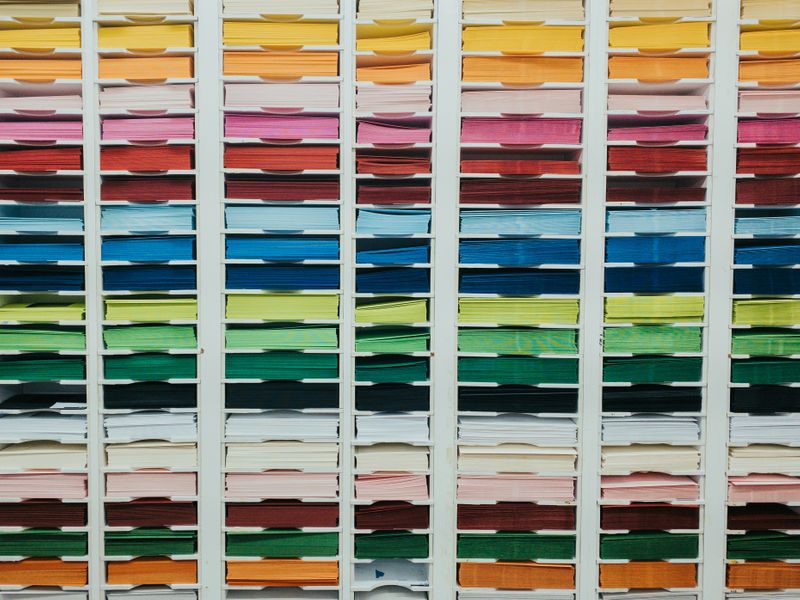 Photo of organized colored construction paper on wall shelf.