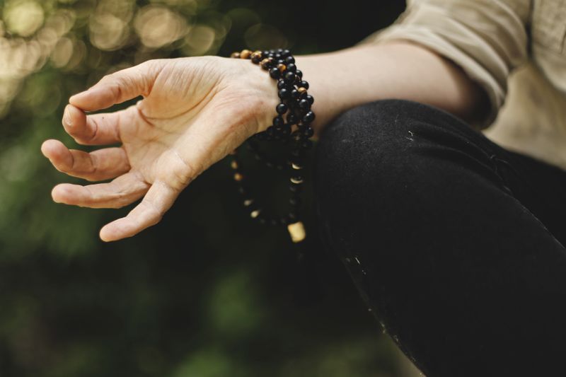 Image of a hand with beads wrapped around, meditating