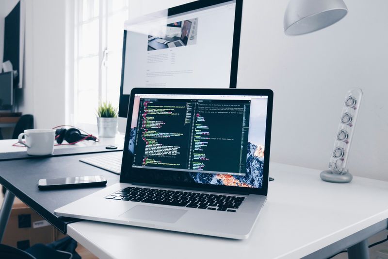 A clean, modern, white workspace with an open laptop and some code on the screen. 