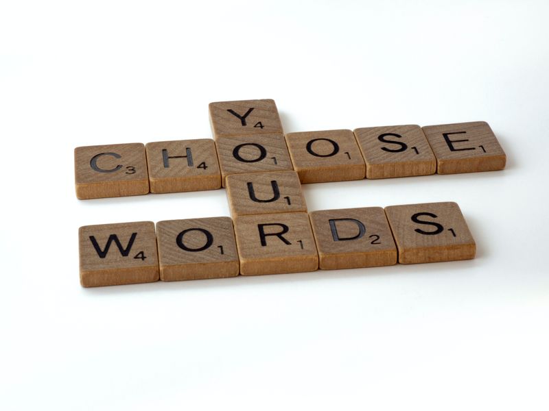 Scrabble tiles spelling out 'choose your words'.