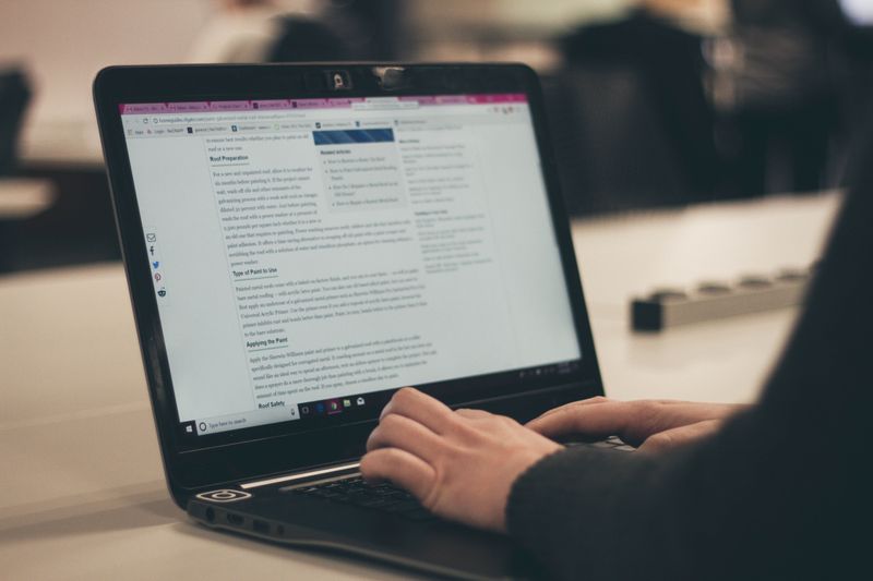 Someone typing on a lap top with words on the screen.