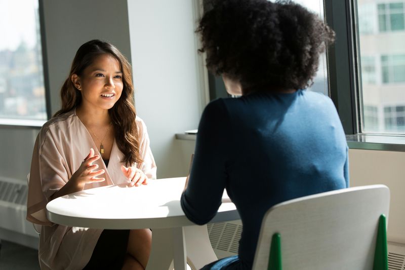 Two women sitting down and talking to each other.