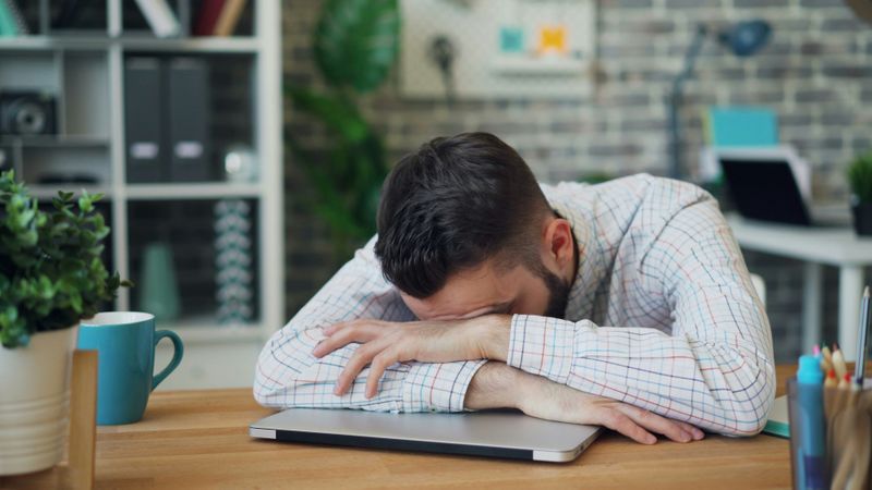 A person puts their head down on their office desk.