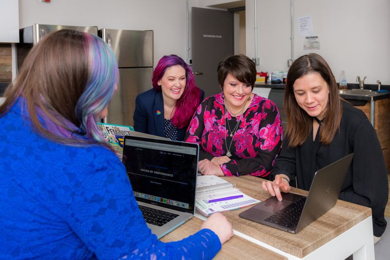 Four women in an office working on laptops