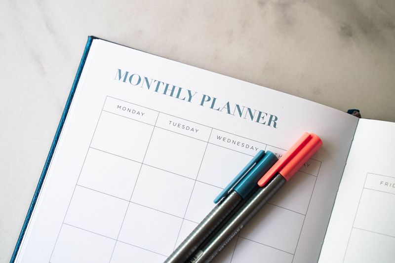 An open monthly planner with two pens on top of a page.