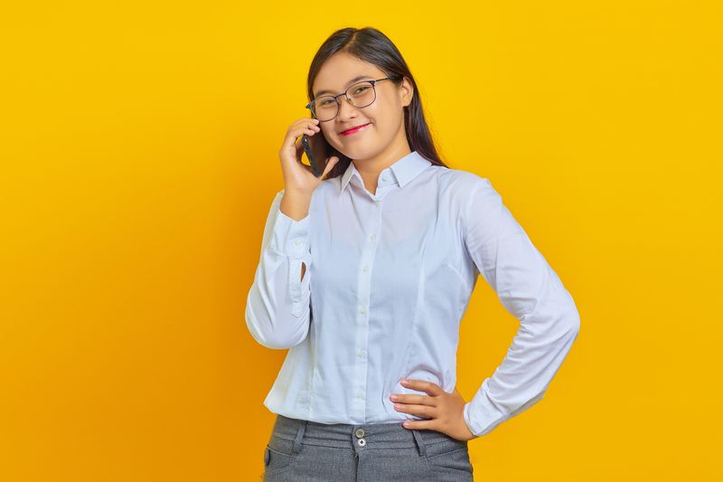 Image: Young lawyer smiling with hand on hip wearing button-up white shirt and yellow background.