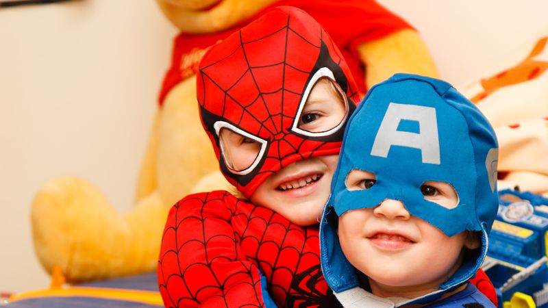 Two young kids dressed in superhero costumes as Spiderman and Captain America