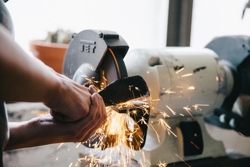 Worker using a grinding machine to shape metal.