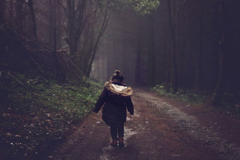 A child walking down a forest path on their own.