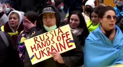 A protestor holding up a sign that says, 'Russia hands off Ukraine.'