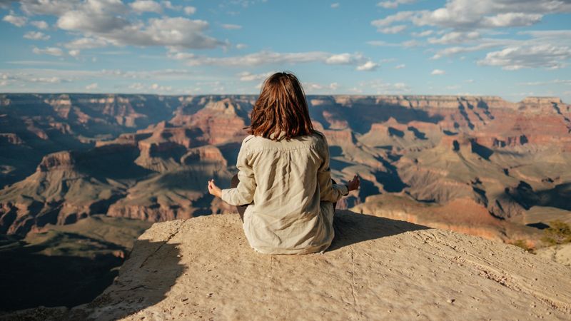 Girl meditating on a rock looking over a valley of red rock formations