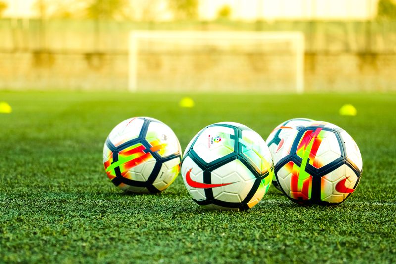 Three footballs on a training pitch practice session.