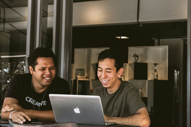 Two people smiling at a laptop.