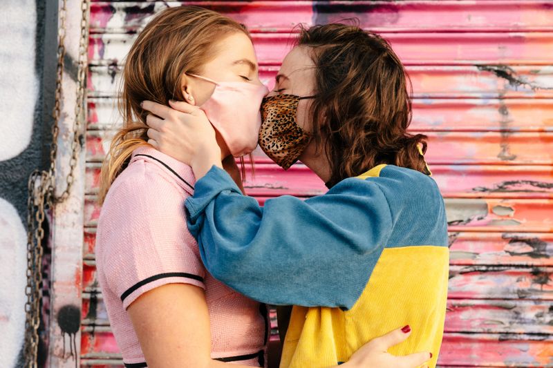 Two people kissing with masks on
