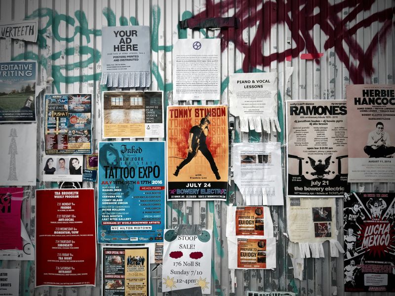 A series of posters on a wall advertising concerts and sales.