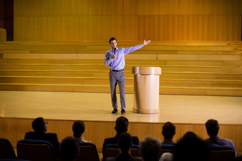 A man speaking on stage to a small audience.