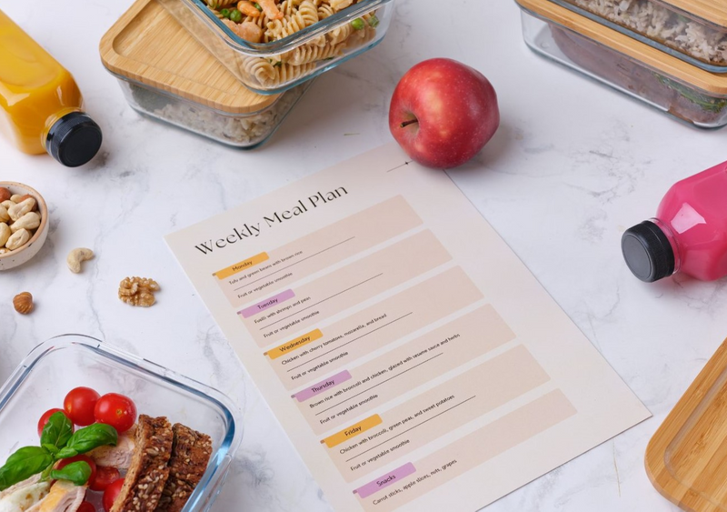 An image with some healthy food items and in the middle it has a sheet for a weekly meal plan. 