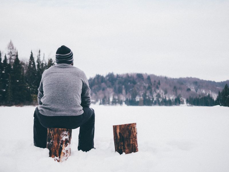man sitting alone on a log in the snow 