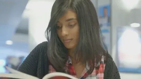 A woman flipping a page while reading a book