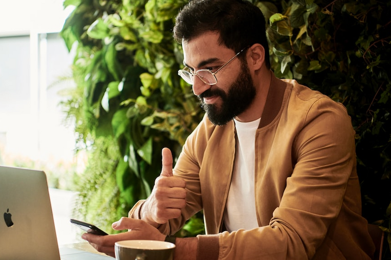 Man looking at his laptop with his thumb up.