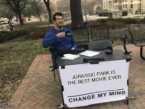 Man sitting at a table and drinking coffee with a sign that says 'Jurassic Park is the best movie ever. Change my mind.'