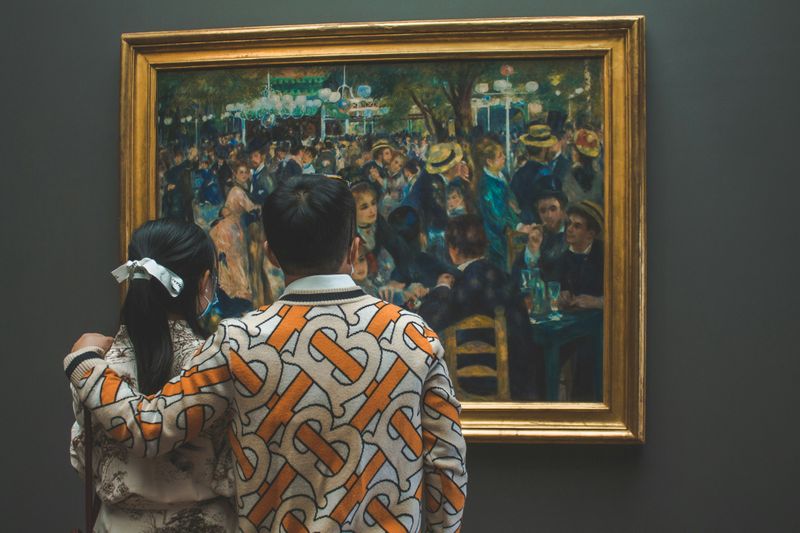 A couple looking at an Impressionist painting in a musuem.