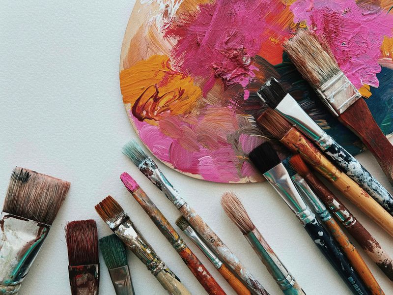 Paintbrushes and a palette covered in paint.