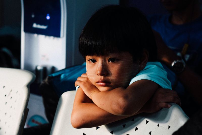 A child looking sad with their chin resting on crossed arms.