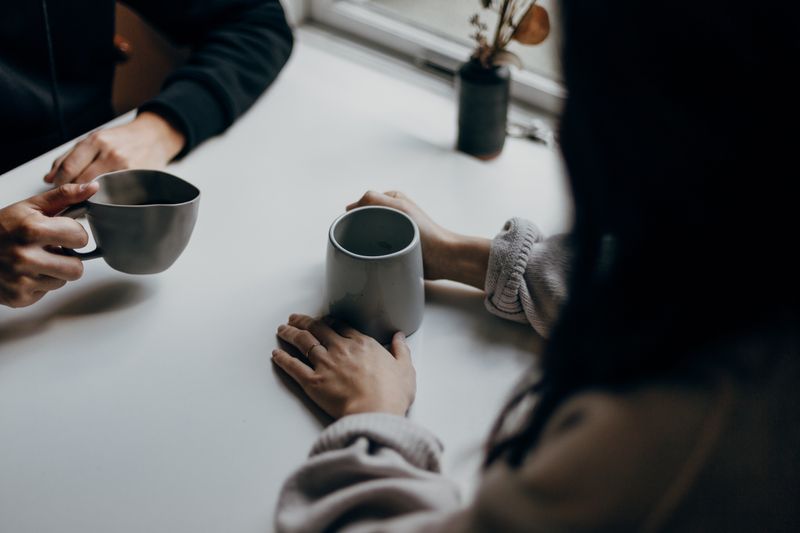 Two people sitting at a table drinking from mugs