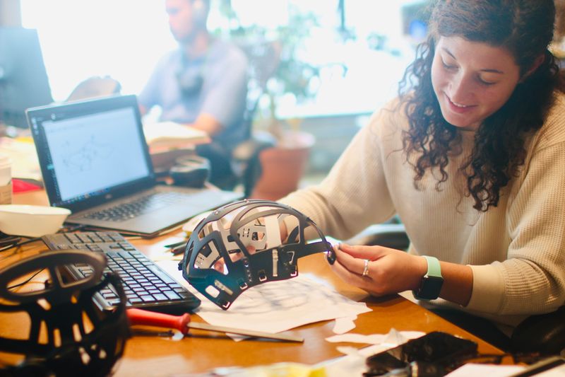 A woman testing a product prototype on her desk at work.