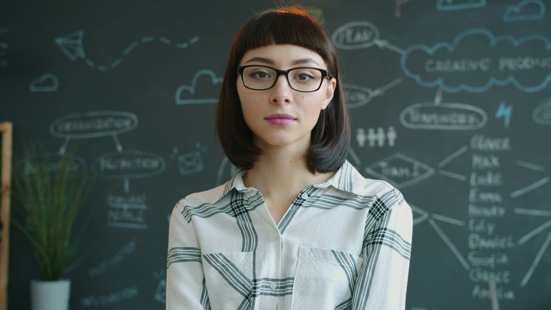 A confident teacher with a chalkboard behind her.