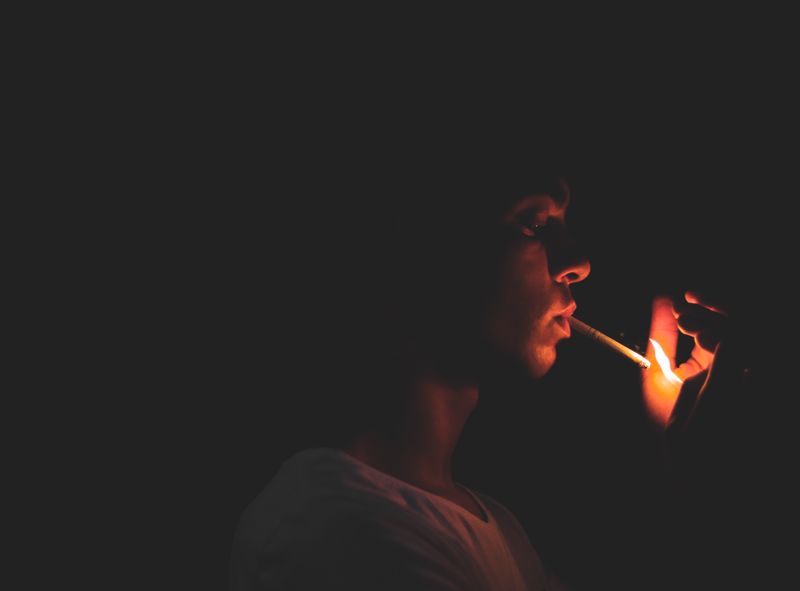 A person in the dark lighting a cigarette.