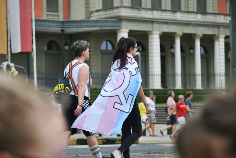 Transgender flag being worn as a cape during a parade.