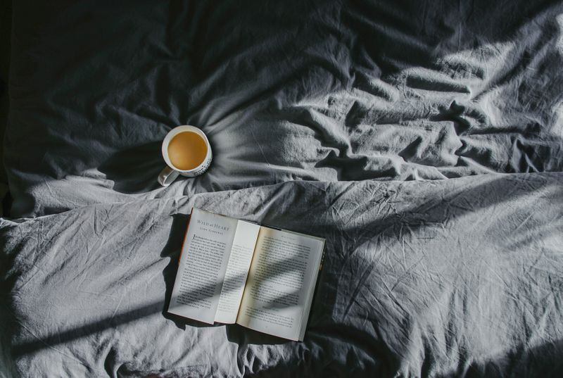 Coffee and a book on a bed.