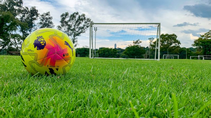 A soccer goal net with a soccer ball in the foreground.