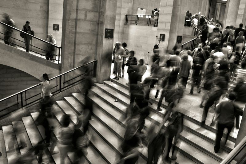 A black and white photo of many people rushing in a bust office building lobby.