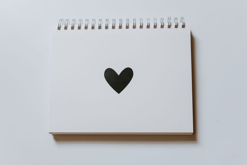 A pad of paper with a black heart on the page